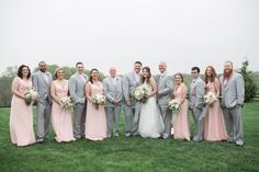 a large group of people standing on top of a lush green grass covered field next to each other