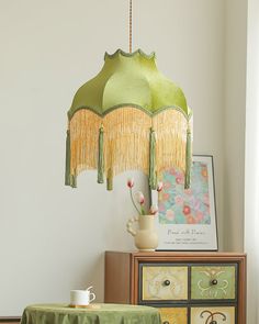 a table with a green cloth on it and a lamp hanging from the ceiling over it