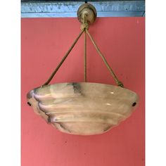 a bowl hanging from a hook on a pink wall