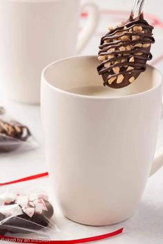 two white cups filled with hot chocolate and candy canes on top of a table