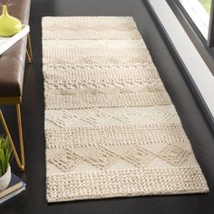 a white rug sitting on top of a black floor next to a chair and window