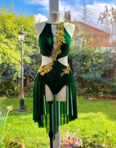 a green and white dress on display in the grass with gold flowers hanging from it's back