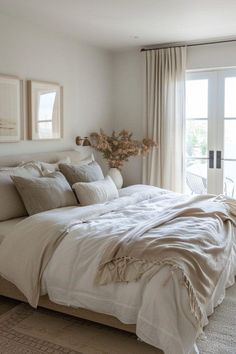 a large bed sitting in a bedroom next to a window covered in white linens