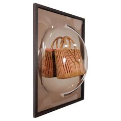 two wicker bags are displayed in a glass case on a white background with black trim