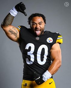 a man in a football uniform with his tongue out and one hand on his hip