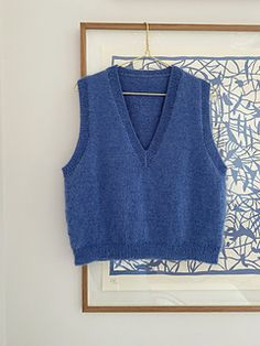 a blue sweater vest hanging on a wall next to a framed photograph and an ornament