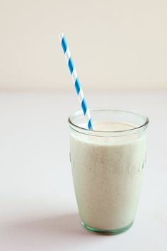 a glass with a blue and white striped straw next to a cup filled with milk