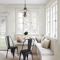 two chairs and a table in a small room with white brick wallpaper on the walls