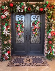 a decorated front door with christmas wreaths and poinsettis on the side