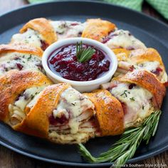 a cranberry and cheese appetizer on a black plate with rosemary garnish