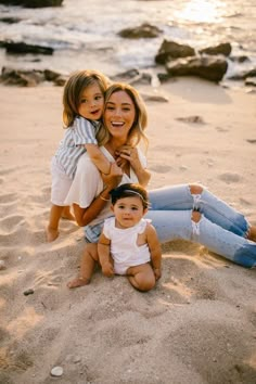 two women and a baby are sitting on the beach