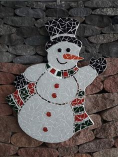 a mosaic snowman on a stone wall