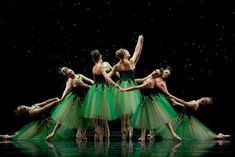 a group of ballerinas in green tutu skirts on stage with their arms extended