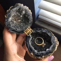 two pieces of black agate with gold rings on them, one being held up by someone's hand