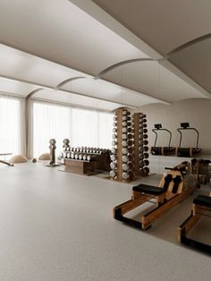 an empty gym with rows of exercise equipment in front of large windows and white walls