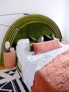 a bed with green headboard and pillows on top of it next to a rug