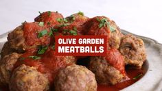 a white plate topped with meatballs covered in marinara sauce and garnished with parsley