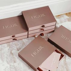 four pink boxes with the word figur on them sitting on a white carpeted floor