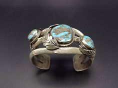 "VINTAGE NAVAJO BRACELET DESCRIPTION: This impressive cuff features a heavy cast sterling silver foundation, embellished with three stunning specimens of brilliant blue Morenci turquoise. This bracelet will be a cherished addition to your collection of fine vintage Native American jewelry. MEASUREMENTS: Interior of the cuff measures 5 1/2\" with an additional 1 1/4\" non-adjustable gap. Total circumference: 6 3/4\" Measures 2 1/2\" straight across the widest part of the cuff (from wrist bone to Vintage Silver Solid Cuff Bracelet, Heavy Vintage Silver Cuff Bracelet, Vintage Sterling Silver Cuff Bracelet With Patina, Traditional Silver Bracelets With Patina, Antique Silver Cuff Bracelet With Patina, Morenci Turquoise, Vintage Native American Jewelry, Navajo Bracelet, Turquoise Bracelet Cuff