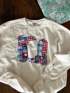 a white shirt with the letter u on it and some other items laying next to it