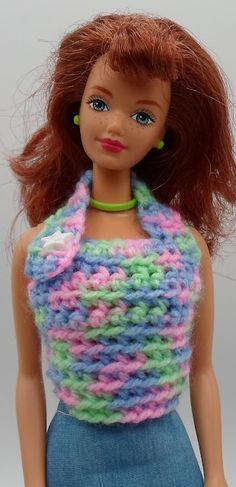 a doll with red hair wearing a multicolored knitted top