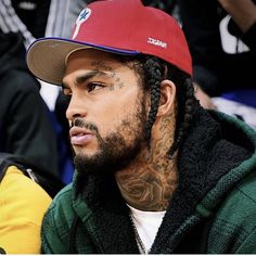 a close up of a person wearing a red hat and green jacket at a basketball game