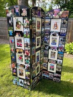 an outdoor display with multiple pictures on it in the middle of some grass near a tree