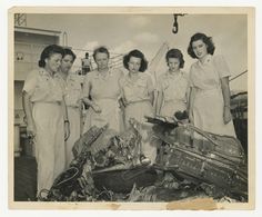 an old black and white photo of four women in uniform standing next to a wrecked car