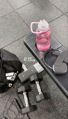 the contents of a gym bag are laid out on the floor next to a water bottle