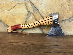 a spotted knife on top of a wooden table next to a stone wall and wood planks