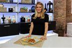 a woman standing in front of a counter holding a plate with food on top of it