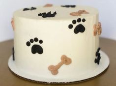 a white cake with black and brown dog paw prints on it