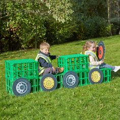 two young children sitting on top of green crates