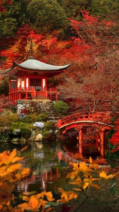 a small red building sitting on top of a lush green hillside next to a lake