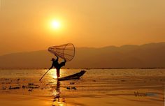 a person standing in the water with a boat on it's back and holding a fishing net over their head