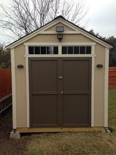 a small shed sitting in the grass next to a fence