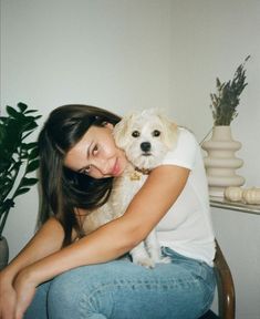 a woman sitting on a chair holding a white dog