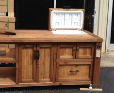 a kitchen island made out of wood with an ice box on top and drawers below