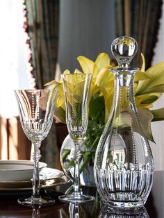 the table is set with wine glasses and yellow flowers