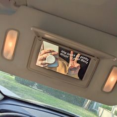 there is a car mirror with the reflection of someone holding up their peace sign in front of them