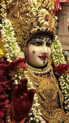 a close up of a person wearing a costume and headdress with flowers in the background