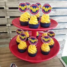 cupcakes with yellow frosting are on a red cake platter that has wonder logo toppers