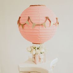 a pink paper lantern sitting on top of a table next to a vase filled with flowers