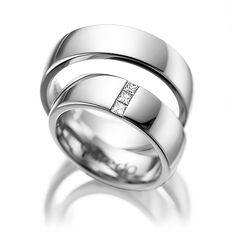 two white gold wedding rings with princess cut diamonds on each side and channel set in the middle