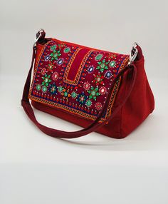 Tikli shisha work, a burgundy messenger bag featuring captivating Indian tribal mirror embroidery on the flap. Crafted from water-resistant outdoor fabric with a cotton lining, it exudes charm and durability. Equipped with a convenient straight bag wrap magnet, two interior pockets (including one with a zipper), and an exterior snap pocket, it offers seamless organization. With dimensions of 12" wide, 7" high, and a 6" base, plus an adjustable handle, it's both compact and versatile. Traditional Red Rectangular Satchel, Traditional Red Satchel Shoulder Bag, Traditional Red Shoulder Bag Satchel, Red Handwork Bag For Everyday Use, Traditional Red Shoulder Satchel, Traditional Red Embroidered Shoulder Bag, Traditional Red Satchel For Travel, Mirror Embroidery, How To Make Purses