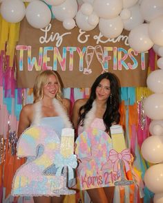 two beautiful women standing next to each other in front of balloons