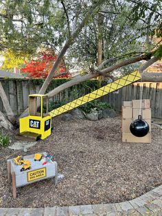 a yellow forklift sitting in the middle of a yard next to a black ball