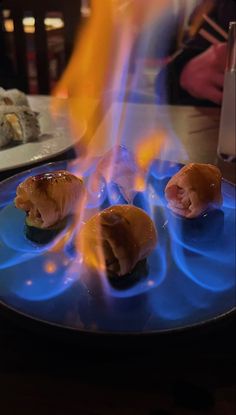 some food is being cooked on a blue plate with flames coming out of the top