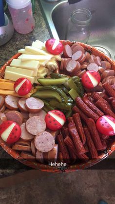 a platter filled with meats, cheese and other foods on top of a kitchen counter