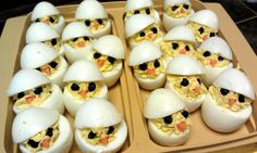 an egg carton filled with deviled eggs topped with black eyes and yellow beaks